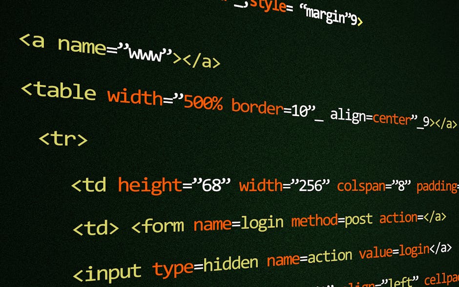 A person wearing a light blue long-sleeved shirt is seated at a white desk, working on a laptop that displays colorful lines of computer programming code on its screen. The person's left hand is holdi